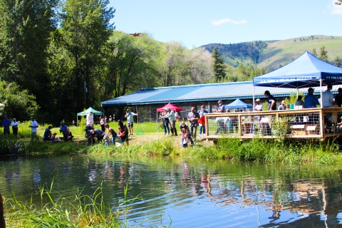 People gather around a trout pond with fishing poles and nets