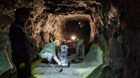 Biologists position a UV-C light in the middle of a cave floor. 