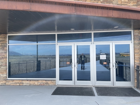 reflection of photographer shown in the highly reflective front entrance doors at the visitor center