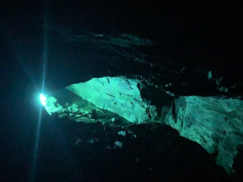 A blue light illuminates the walls of a cave.