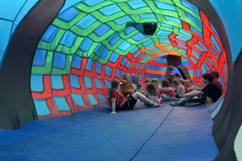 a group of kids gather inside a colorful blow-up fish tent