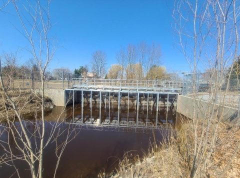 A metal, dam-like structure spans a river. 