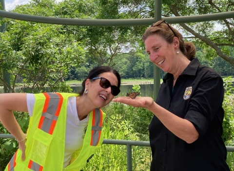 Director Martha Williams and Assistant Secretary Shannon Estenox admire a monarch butterfly perched on Martha's outstretched palm